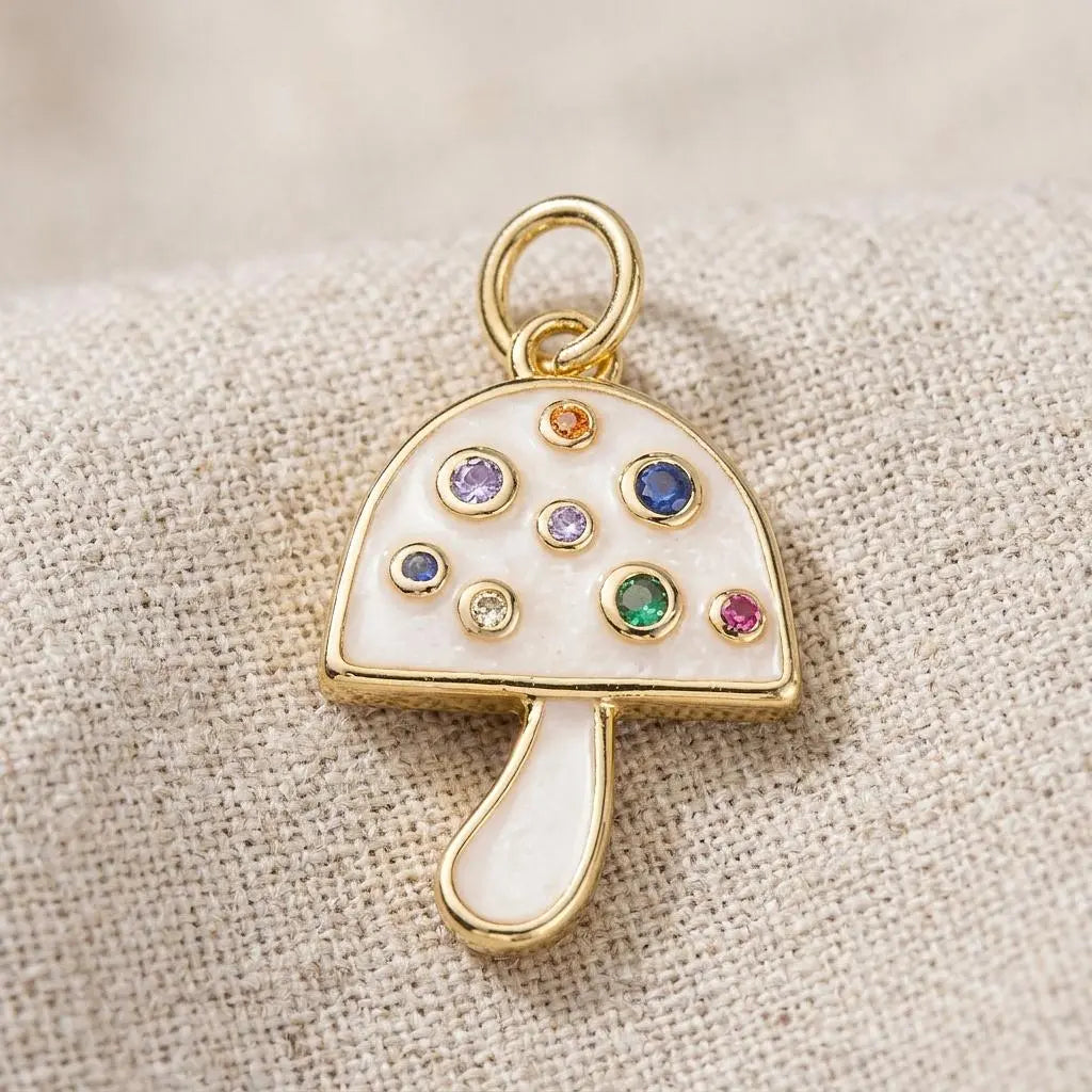 Gold and pearlescent mushroom charm jewelry by Winks Design Studio, LLC, featuring a detailed, shiny mushroom pendant.
