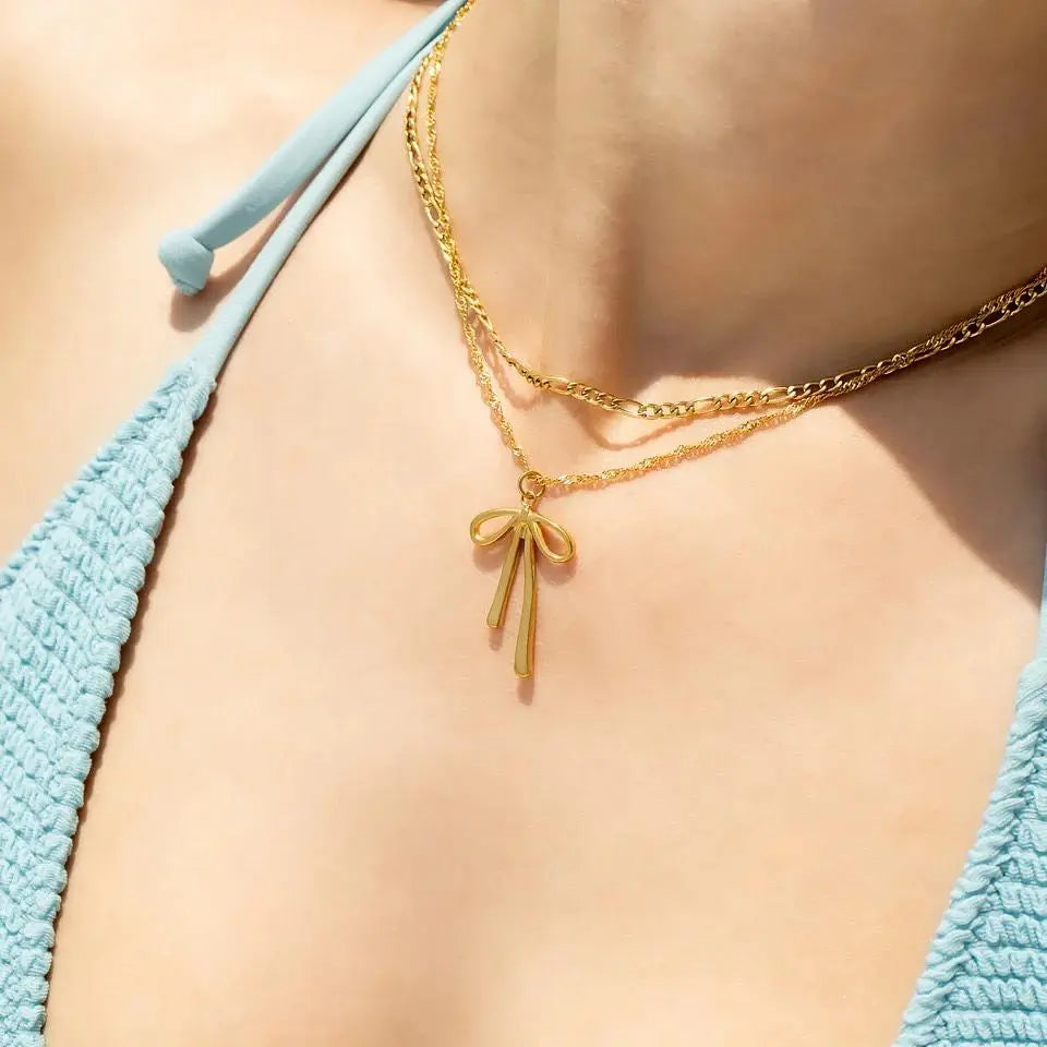18K gold long bow charm from Winks Design Studio, LLC, featuring a detailed, elegant bow design for jewelry or accessories.