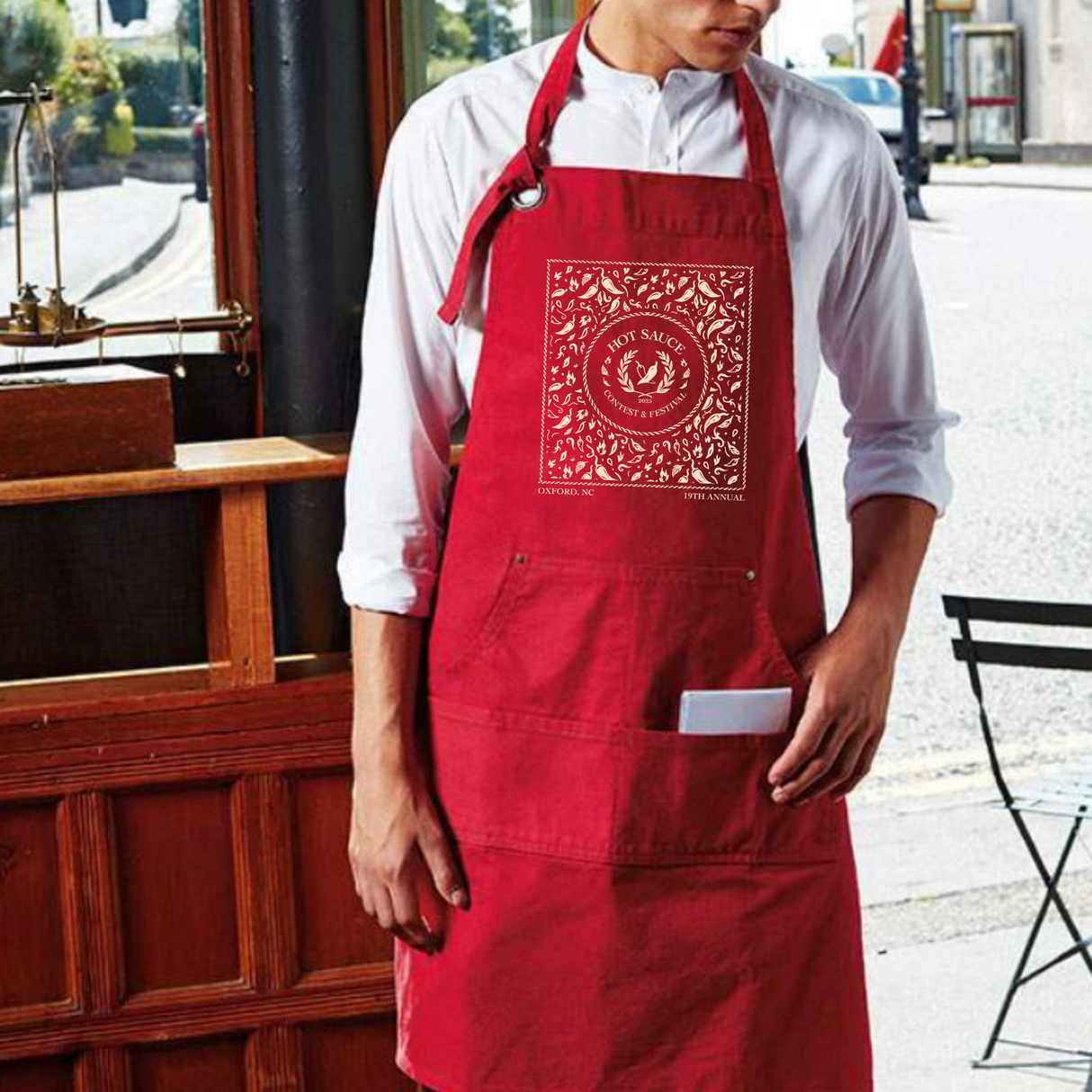 Person wearing a red apron with a white logo in an outdoor setting