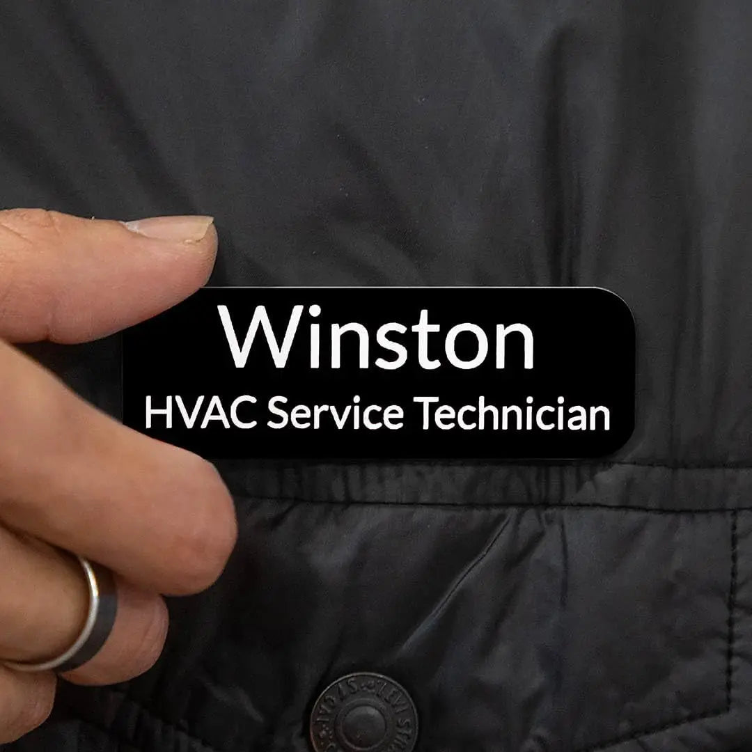 Custom engraved magnetic name badge with Winks Design Studio branding, featuring a professional design and magnetic fastening.