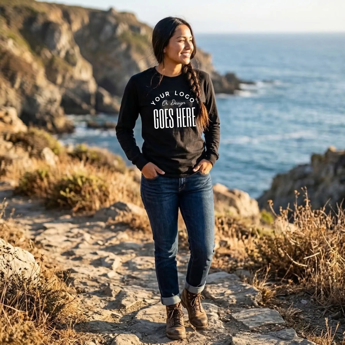 Woman in a black custom long sleeve t-shirt with a white "Your Logo or Design Goes Here" center chest placeholder on a coastal trail