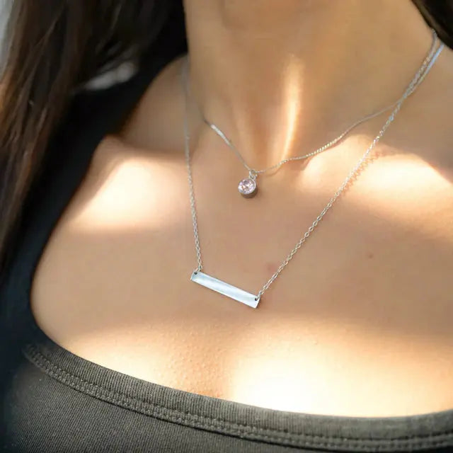 18K gold engraved bar necklace from Winks Design Studio, personalized stainless steel jewelry, close-up of sleek, minimalist pendant.