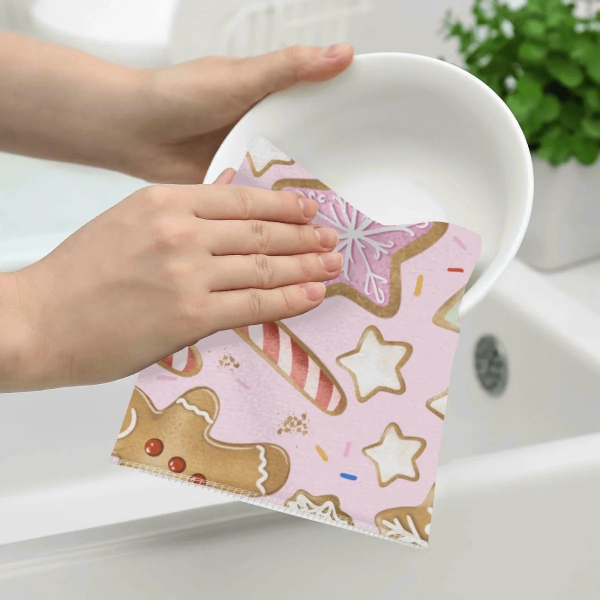 Hand holding a pink towel with gingerbread men design over a white bowl.