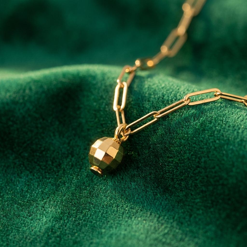 Gold disco ball charm from Winks Design Studio jewelry collection, shiny spherical pendant with reflective surface.