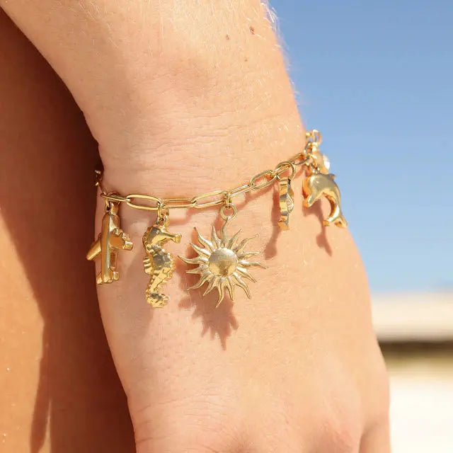 Gold sea charm from Winks Design Studio, LLC featuring intricate ocean-inspired details for jewelry or accessories.