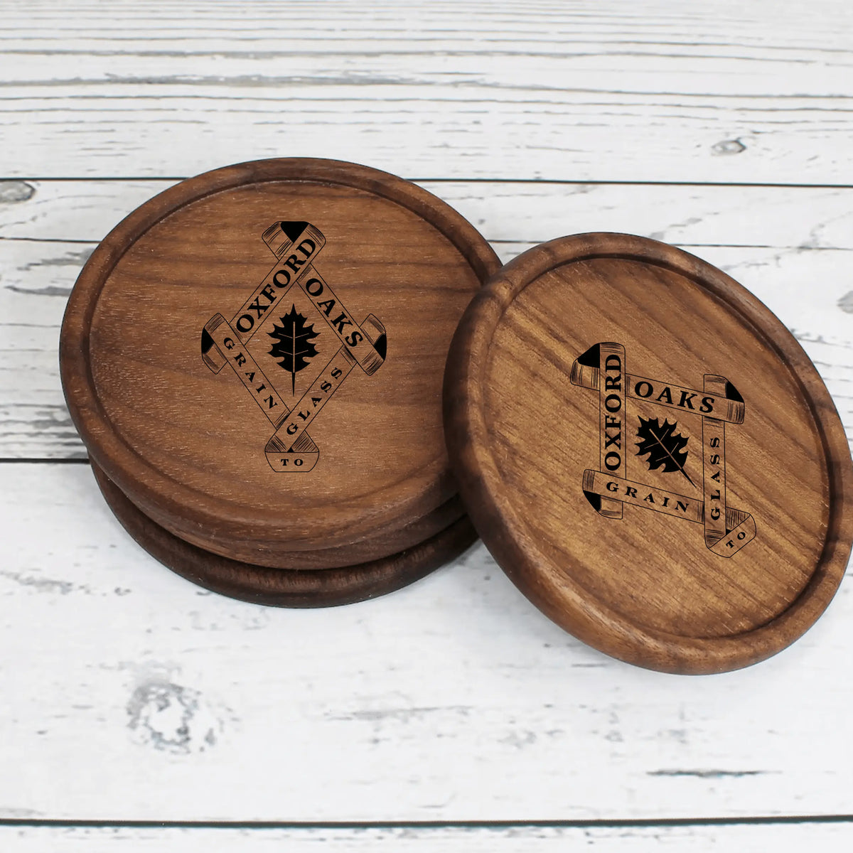 Wooden engraved coasters from Oxford Oaks Distillery by Winks Design Studio, LLC, featuring detailed engraved designs.