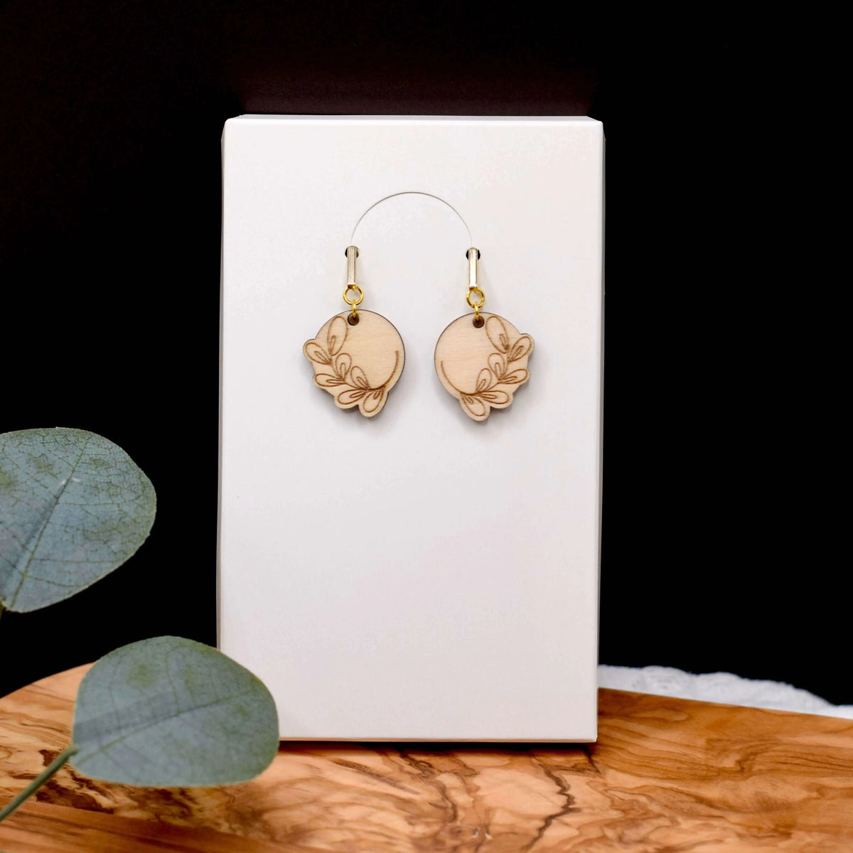 Wooden engraved eucalyptus earrings by Winks Design Studio, LLC, showing detailed carved eucalyptus leaf design on natural wood earrings.
