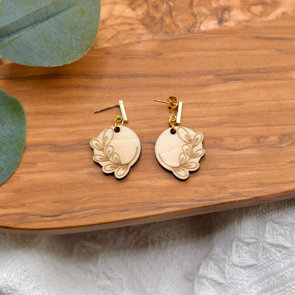 Wooden engraved eucalyptus earrings by Winks Design Studio, LLC featuring natural wood texture and intricate engraved details.