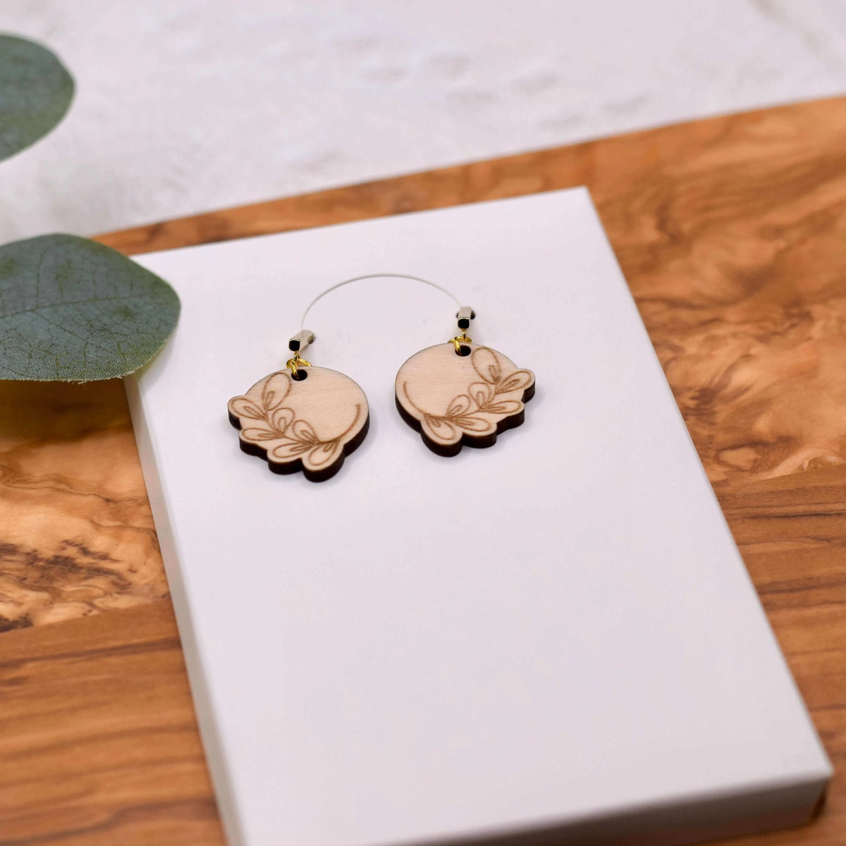 Wooden engraved eucalyptus earrings by Winks Design Studio, LLC featuring detailed carved leaf patterns on natural wood earrings.