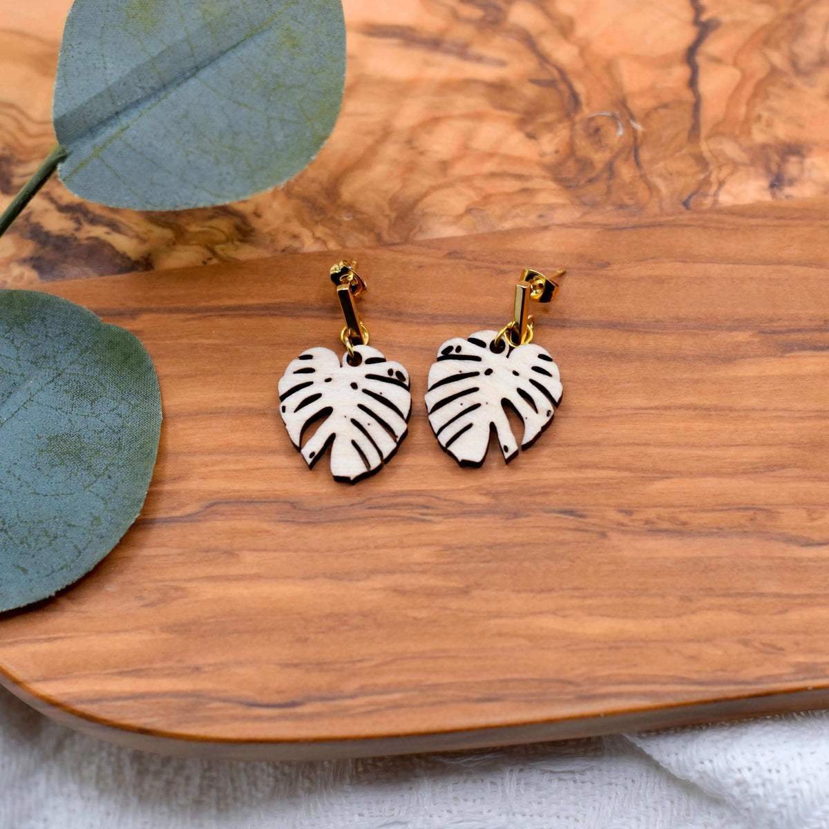 Wooden Monstera leaf earrings by Winks Design Studio, LLC, featuring natural, handcrafted leaf-shaped jewelry.