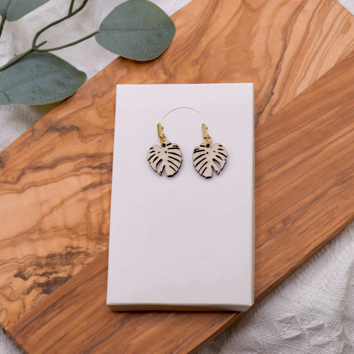 Wooden Monstera leaf earrings by Winks Design Studio, LLC, featuring natural wood texture and tropical leaf design.