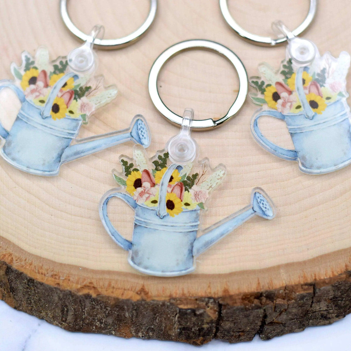 Winks Design Studio LLC watering can keychain with colorful flower charms, detailed metal design, and small hanging loop.