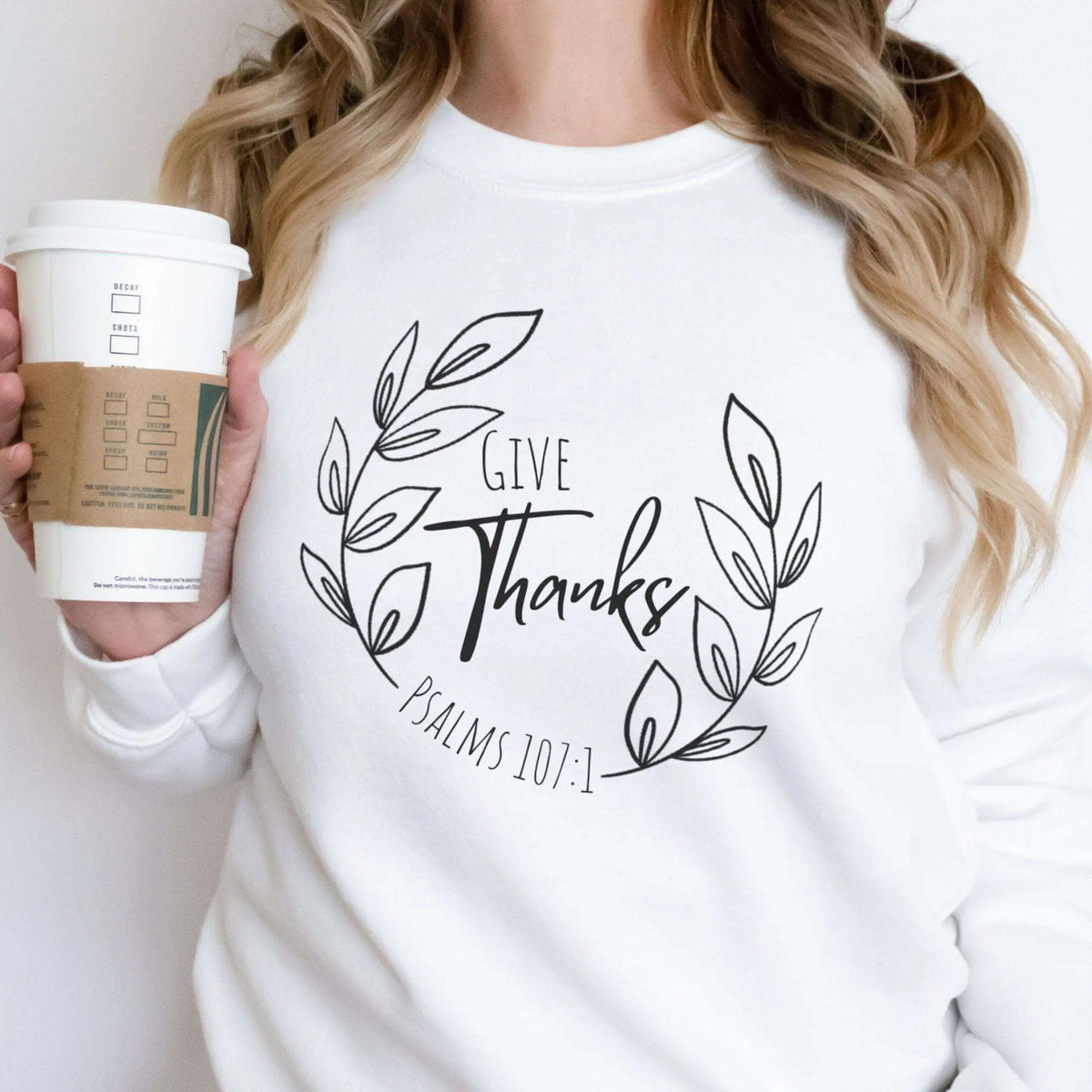 Long sleeve shirt featuring Give Thanks Psalm 107:1 design by Winks Design Studio, LLC, with decorative text on a soft fabric background.