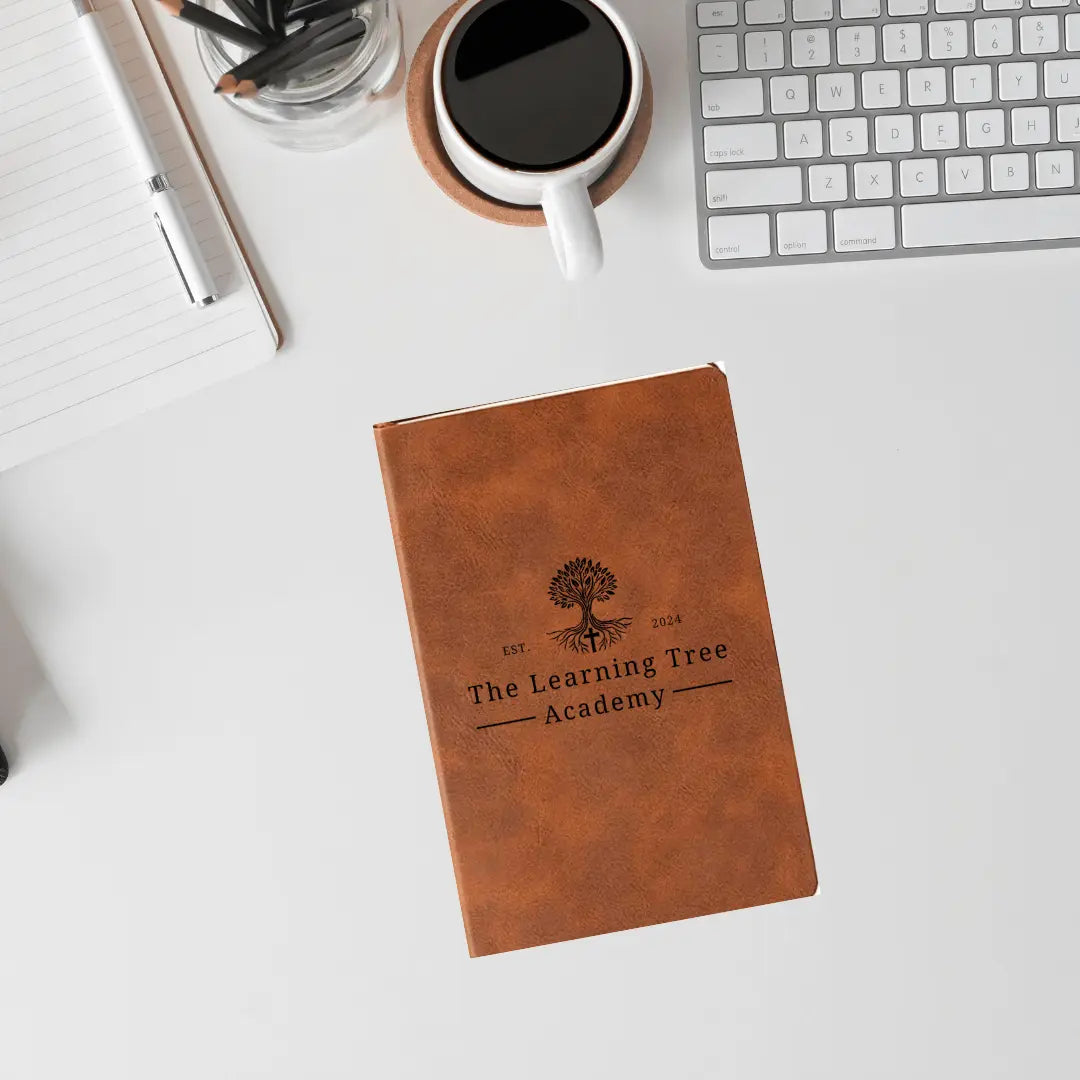 Winks Design Studio leather journal with "The Learning Tree Academy" title, featuring a textured brown cover and lined pages.