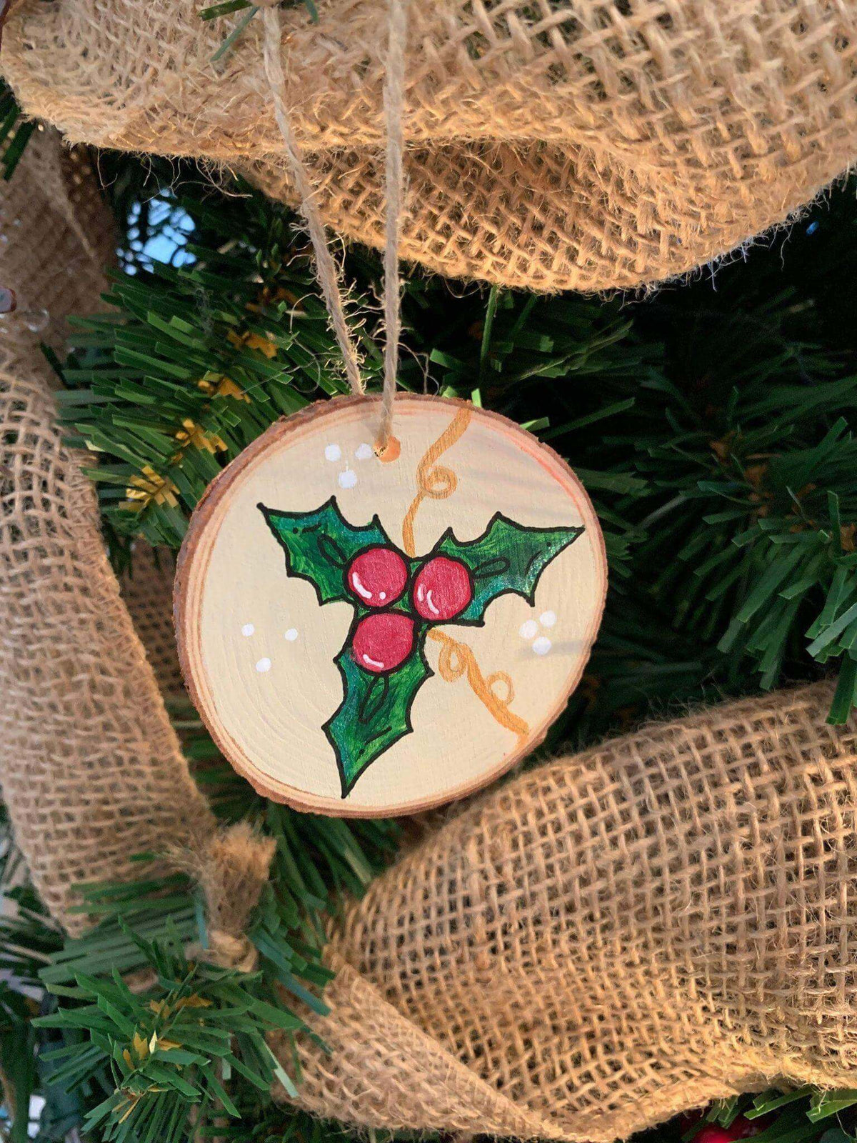 Christmas ornament featuring holly leaves and berries by Winks Design Studio, LLC, with festive holiday design and detailed foliage.
