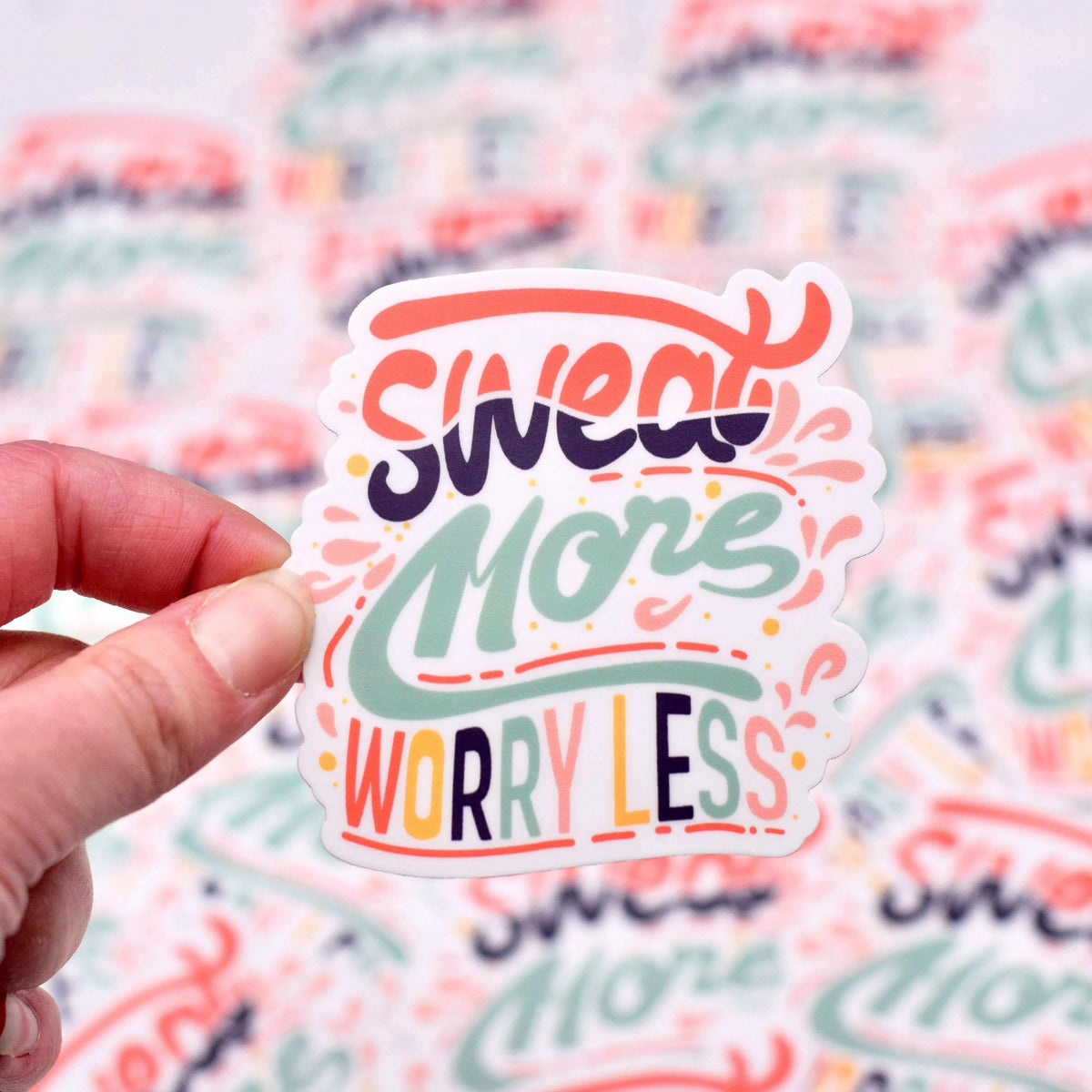 Vinyl sticker with "Sweat More Worry Less" phrase by Winks Design Studio, LLC, featuring bold black lettering on a clear background.