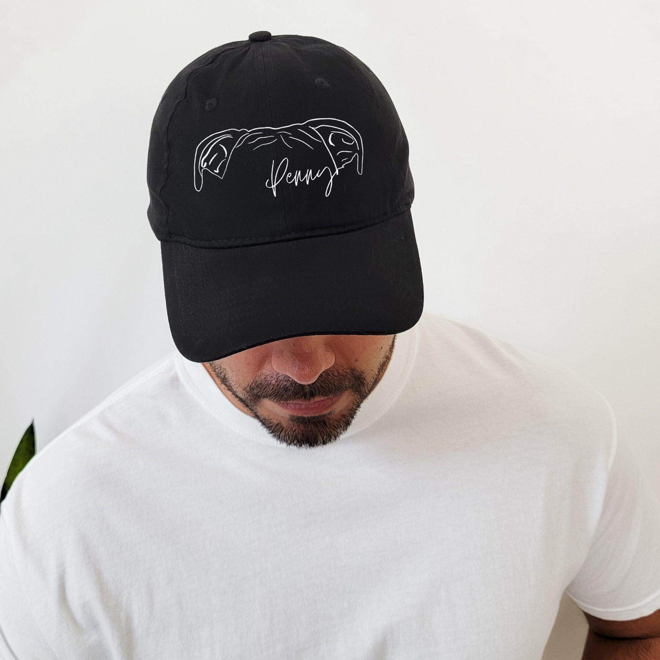 A man wearing a black hat with a dog outline on it.