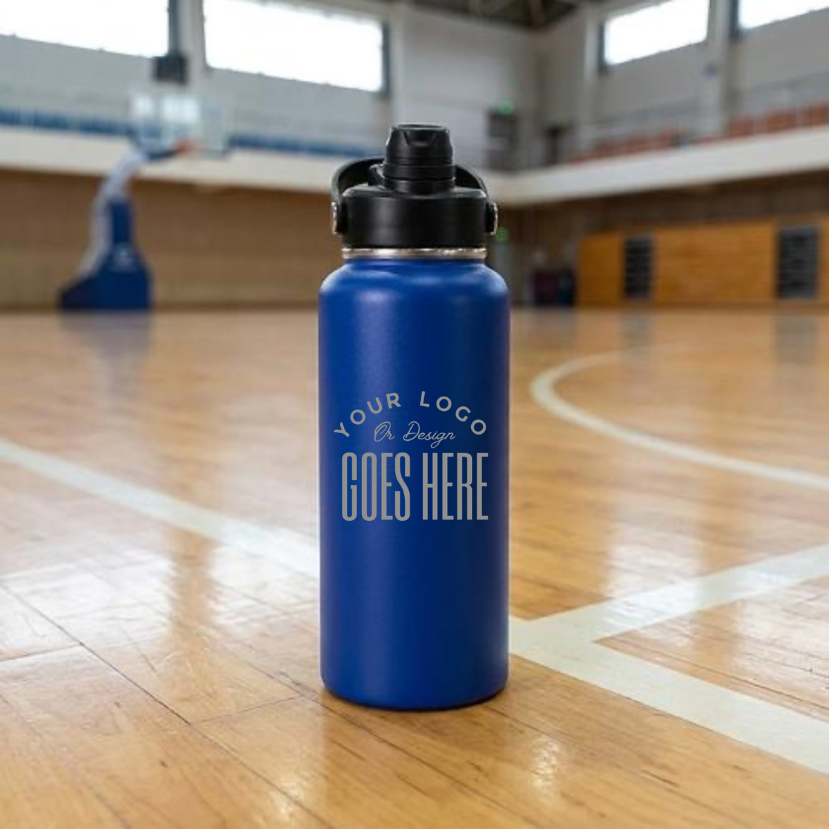 A blue insulated water bottle with a black flip-top lid stands on a polished wooden basketball court. The bottle has a white printed placeholder logo that reads &
