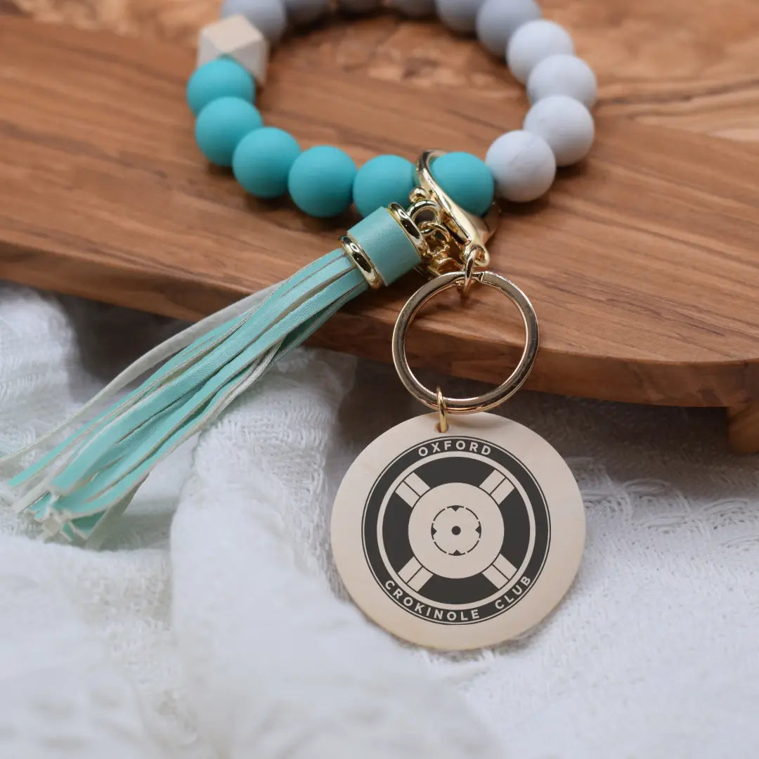 Engraved Oxford Crokinole Club wristlet keychain by Winks Design Studio, LLC with detailed design and keyring attachment.