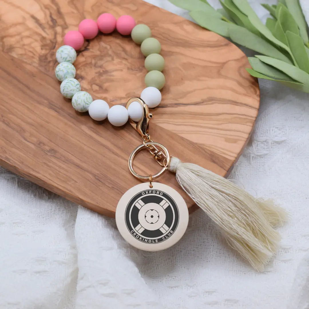Engraved Oxford Crokinole Club wristlet keychain with intricate design and keyring, made by Winks Design Studio, LLC.