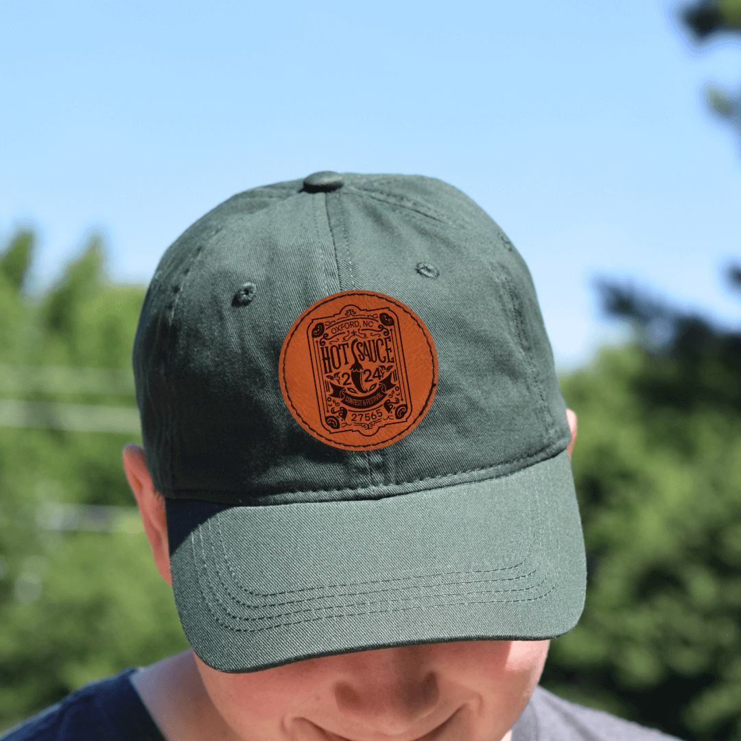 Person wearing NC Hot Sauce Contest & Festival Twill Hat with Vintage Label Design on a sunny day.