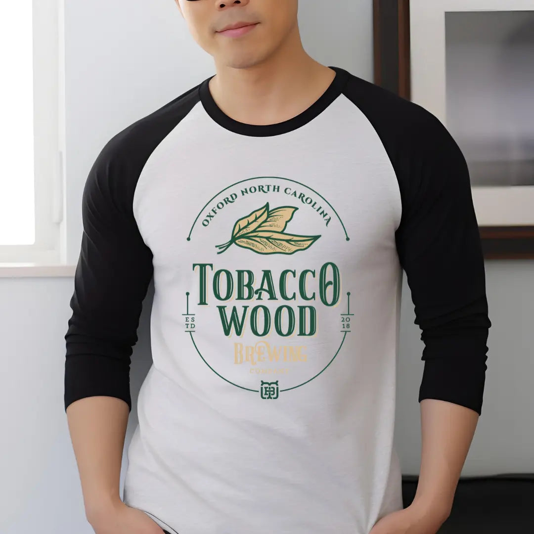 Winks Design Studio LLC Tobacco Wood Brewing Raglan shirt featuring a vintage-style graphic on a black fabric.