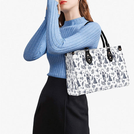 Woman in a blue sweater holding a stylish white handbag with floral print, showcasing modern fashion.