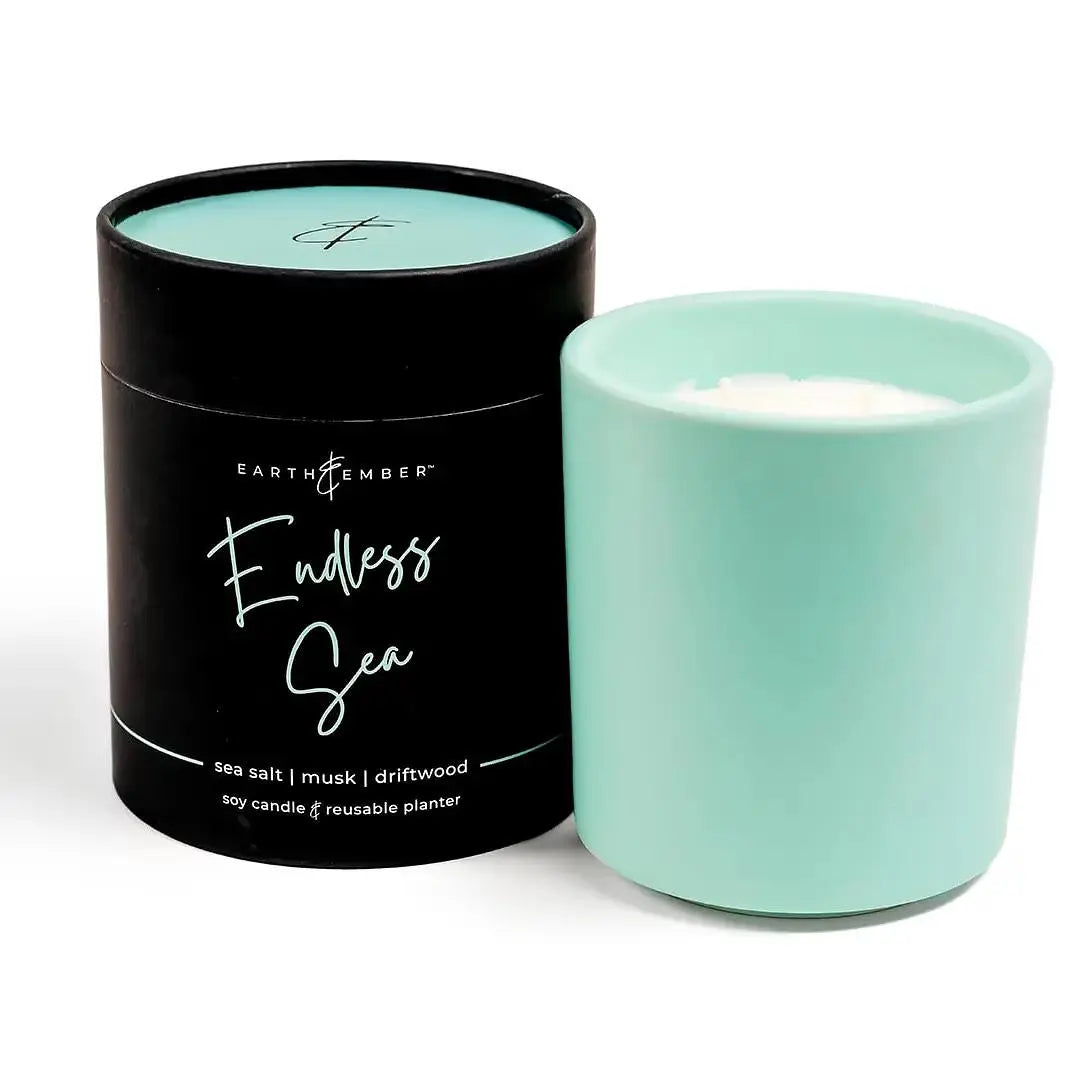 Earth &amp; Ember 13 oz candle by Winks Design Studio featuring a glass jar with a flickering flame and a calming sea-inspired design.
