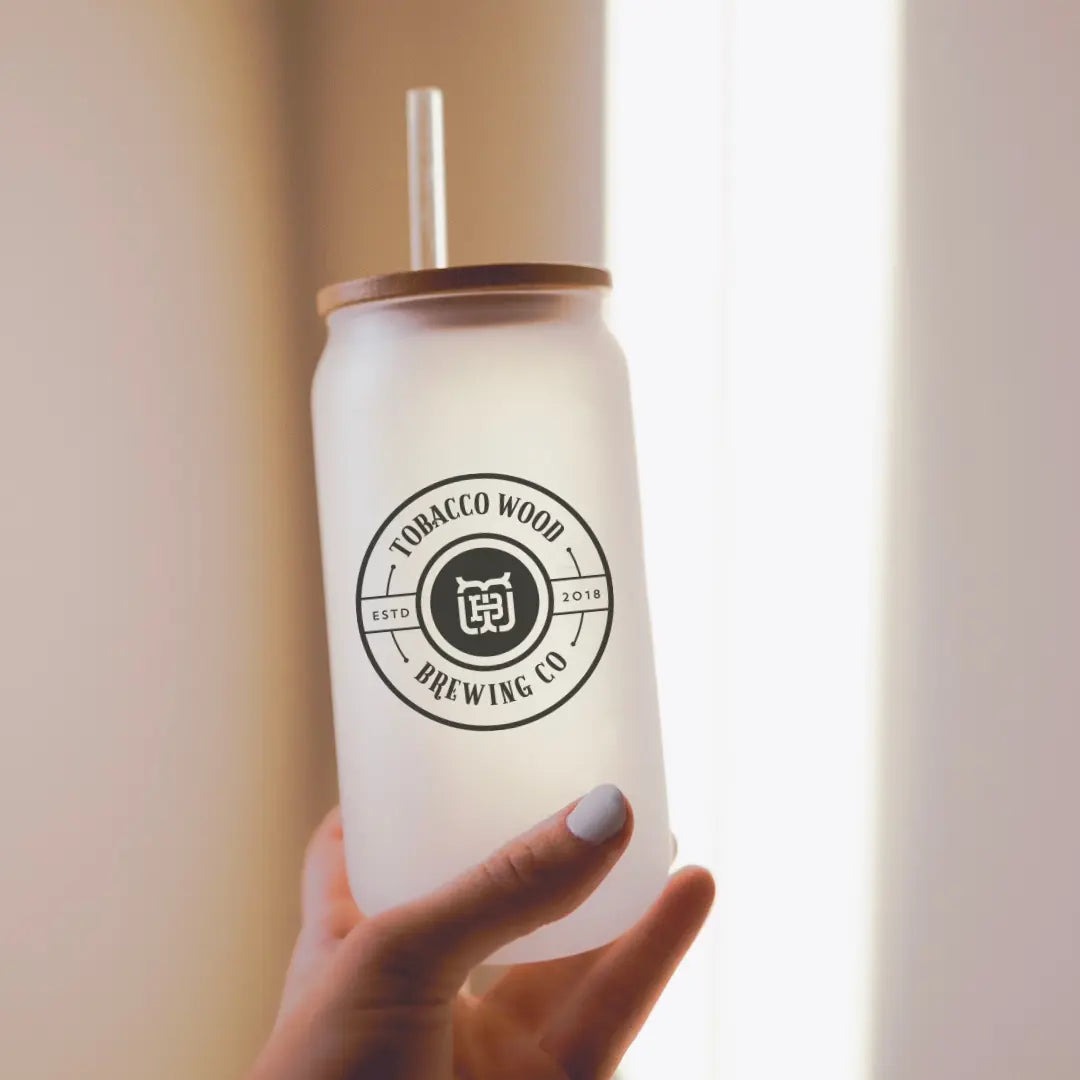 Winks Design Studio Tobacco Wood Brewing 16oz glass can used as drinkware with a clear glass body and tobacco wood design.