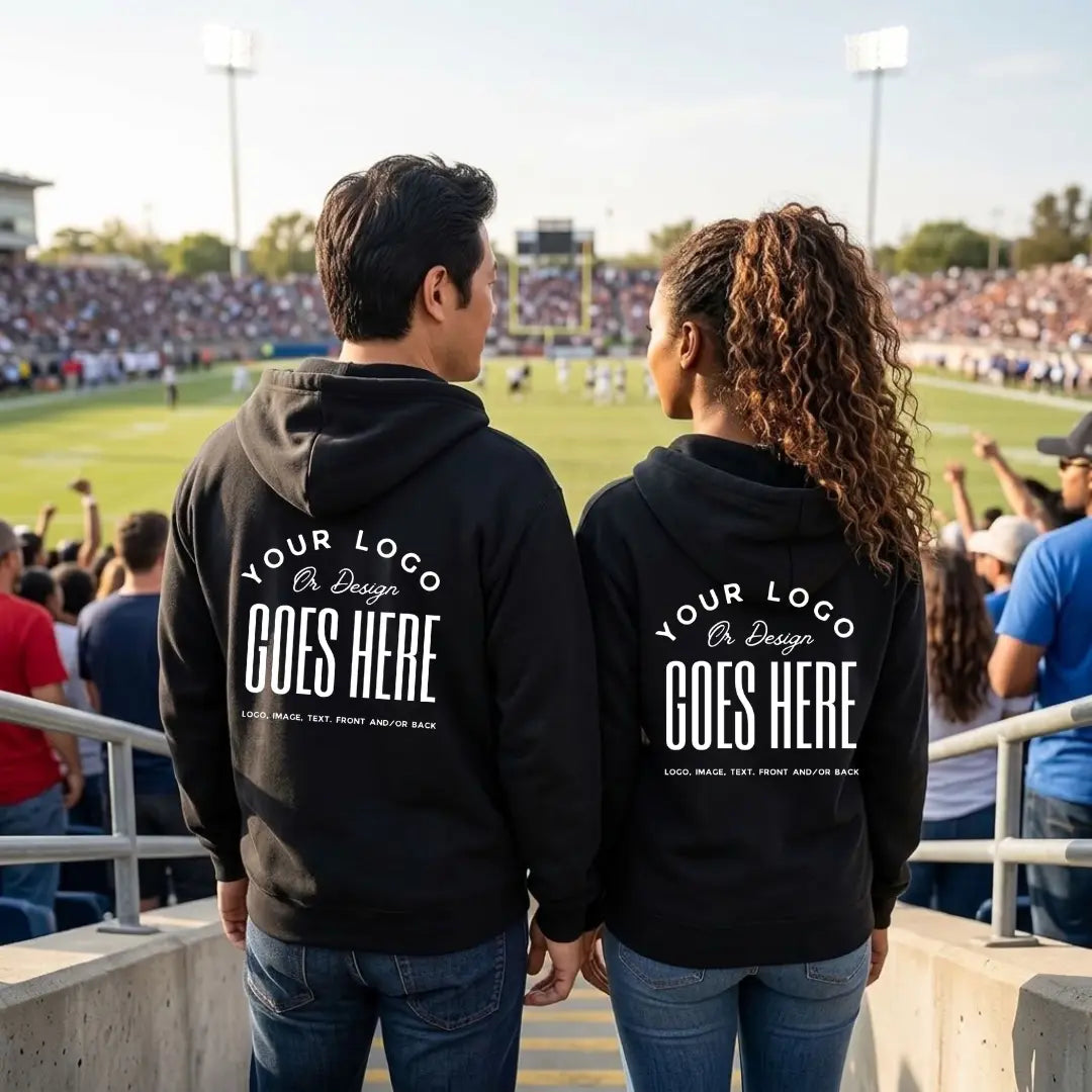 Back view of two people in black custom hoodies with white "Your Logo or Design Goes Here" back placeholder prints at a football game