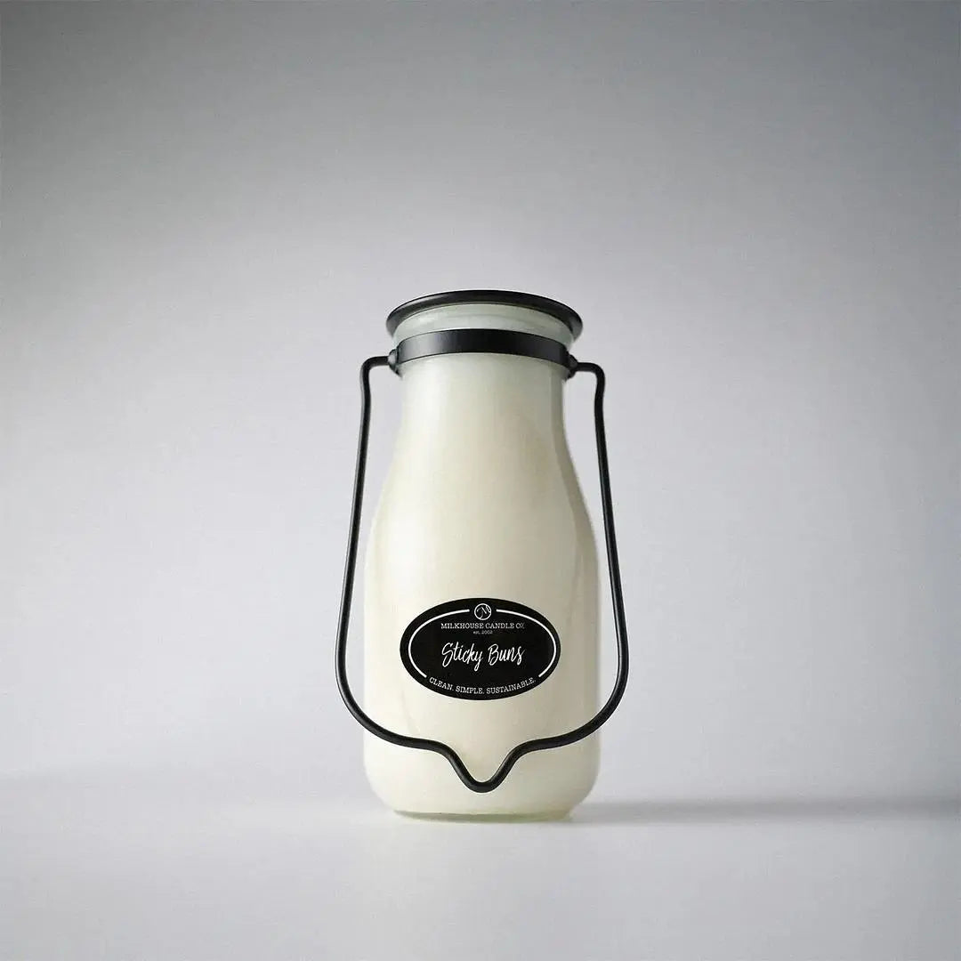 Winks Design Studio LLC Milkhouse Candle 14oz Sticky Buns scented candle with a glass jar and wooden lid, showing a warm, inviting glow.