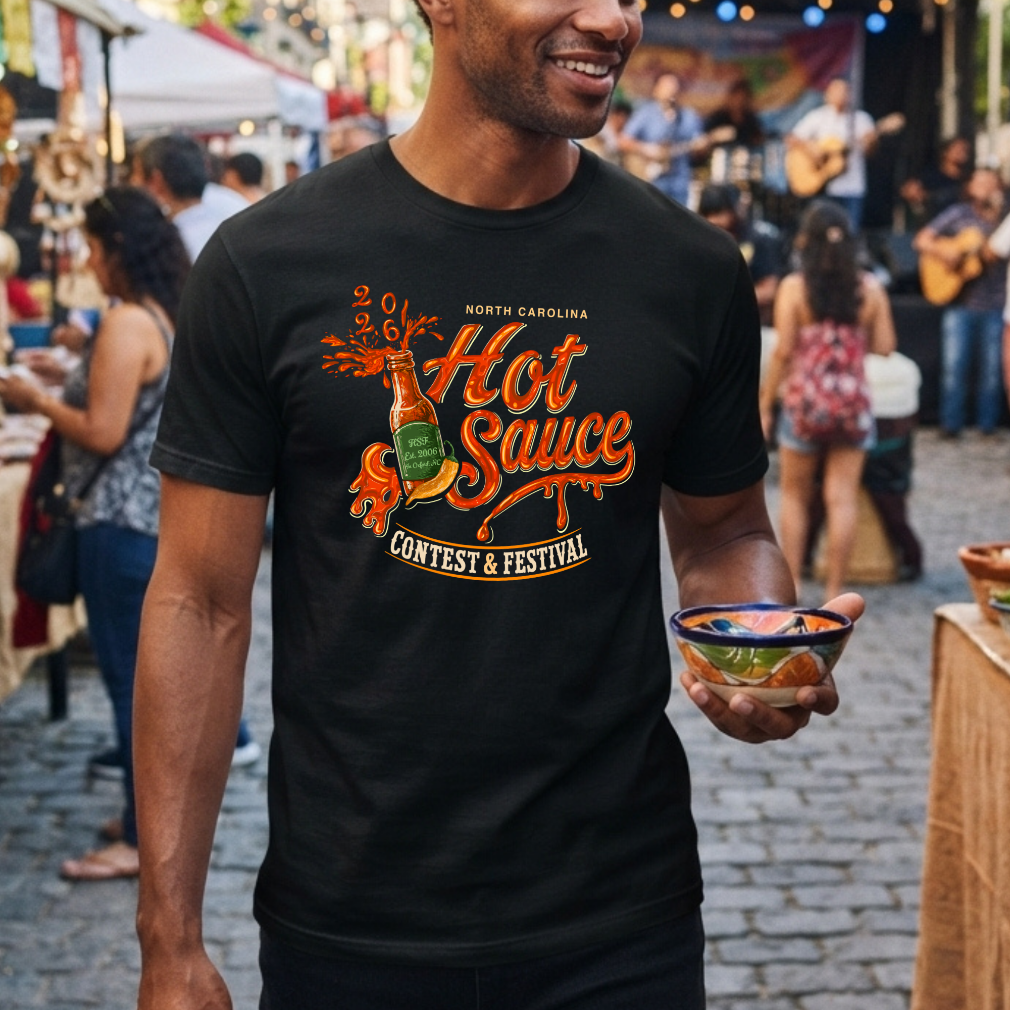 Winks Design Studio LLC NC Hot Sauce Festival Bottle T-Shirt featuring colorful hot sauce bottle graphic on black fabric.