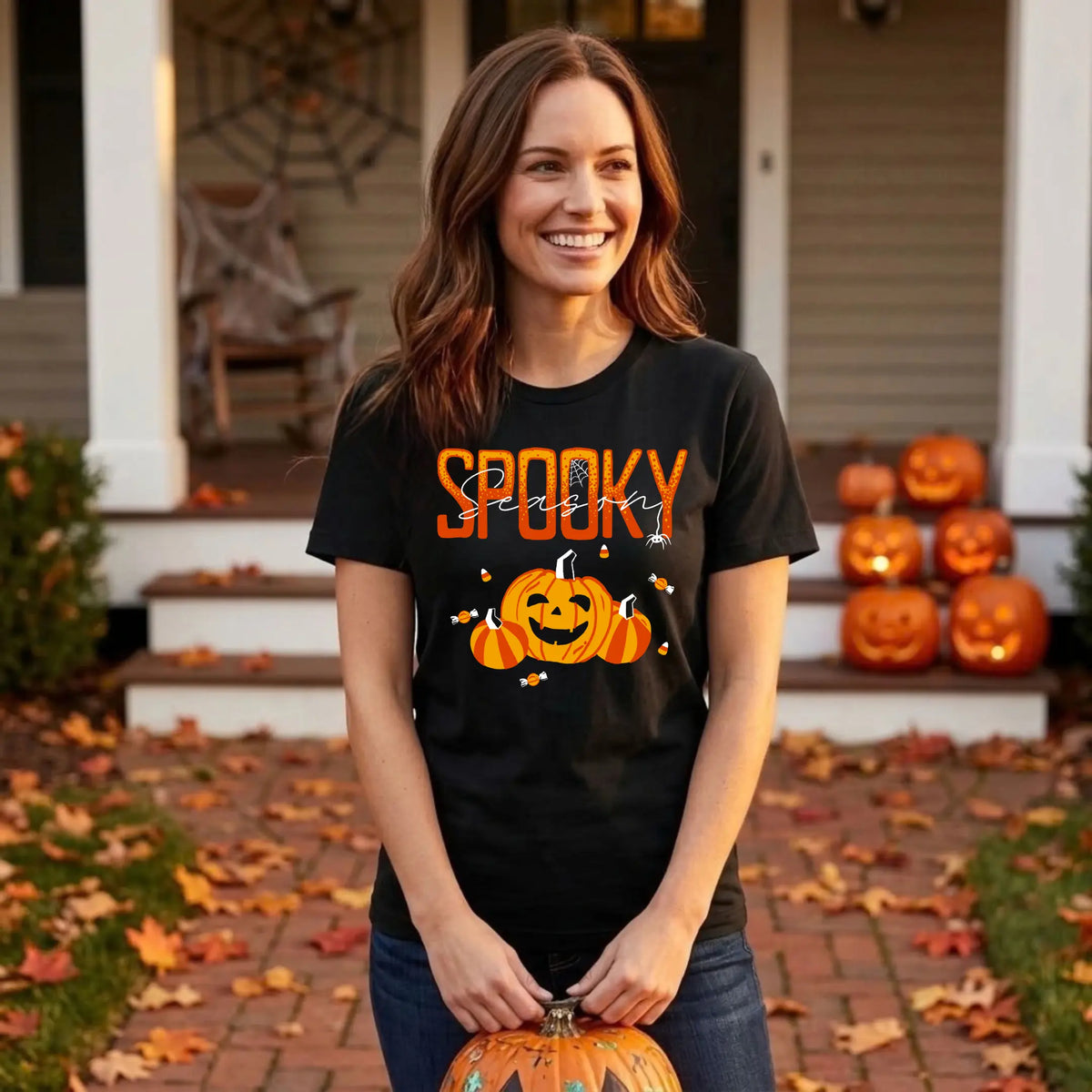 Smiling woman in a black "Spooky Season" Halloween graphic tee holding a jack-o&