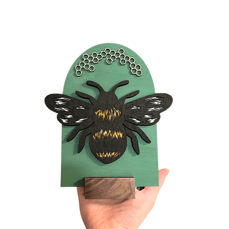 Handcrafted Bee Shelf Sign with unique hand-painted design, featuring a detailed bee and honeycomb on a green background.