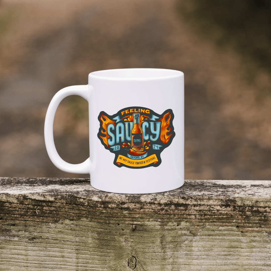 NC Hot Sauce Festival ceramic mug with "Feeling Saucy" design, perfect for hot beverages and celebrating the 2024 event.