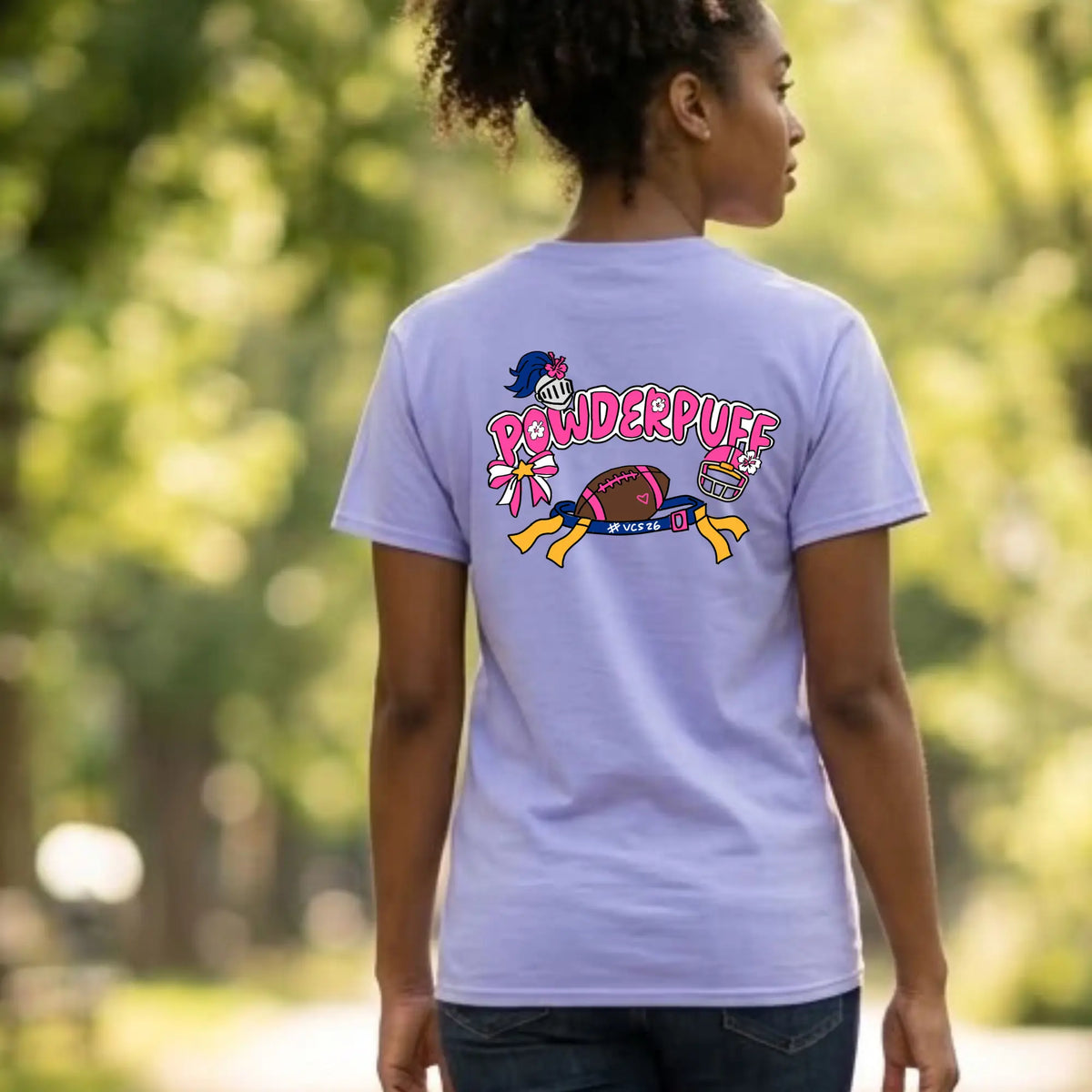 A woman shown from behind wearing a light lavender-purple t-shirt with a colorful &