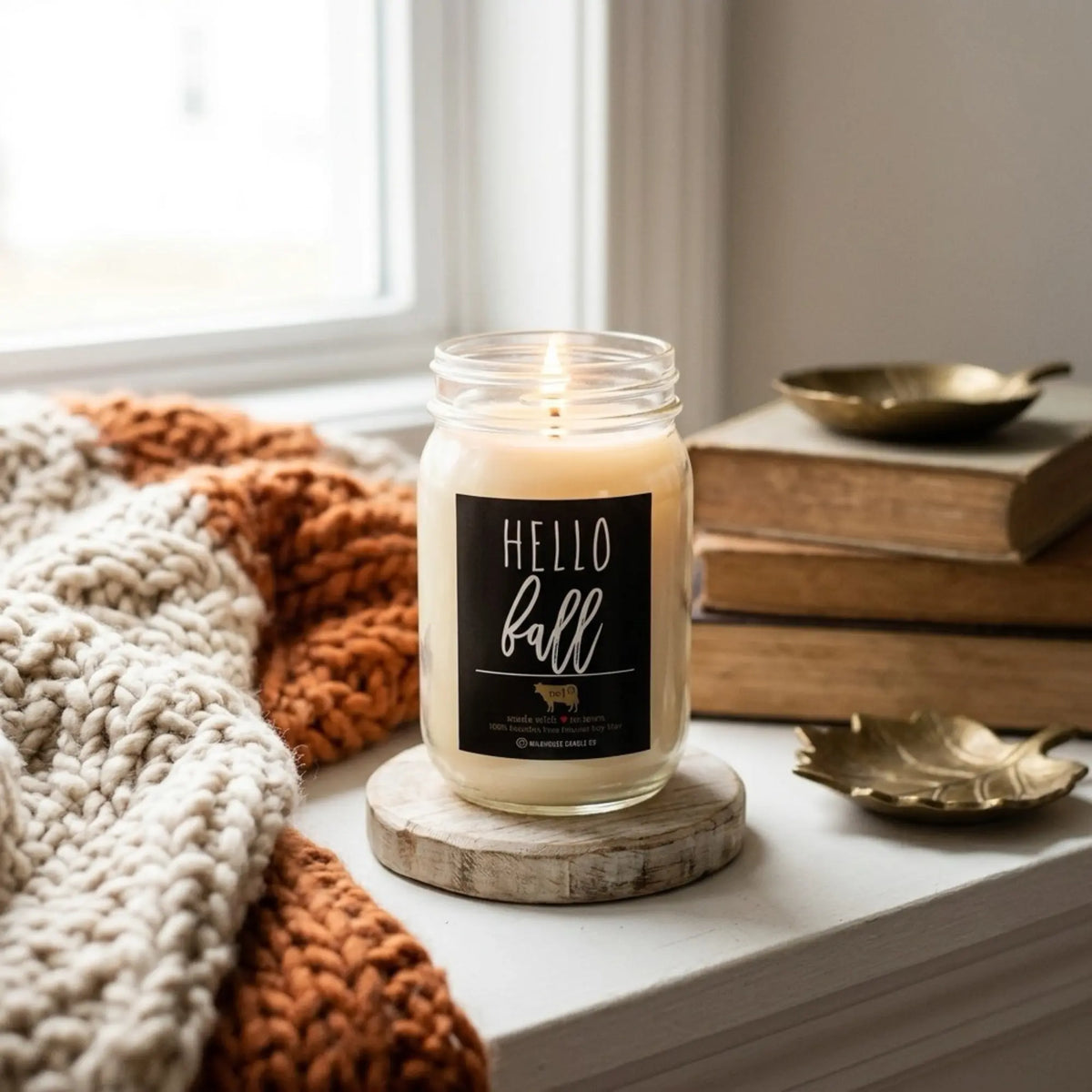 A lit jar candle with a black label reading &