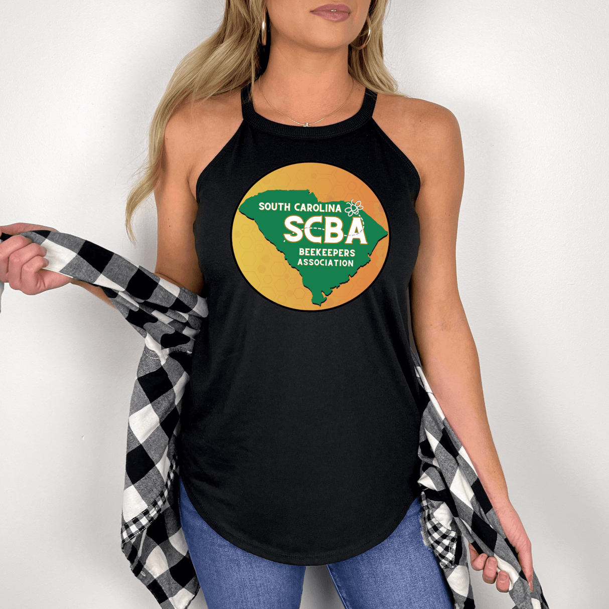 Woman wearing SCBA Halter Tank top in black, showcasing South Carolina Beekeepers Association logo, paired with blue jeans and plaid shirt.