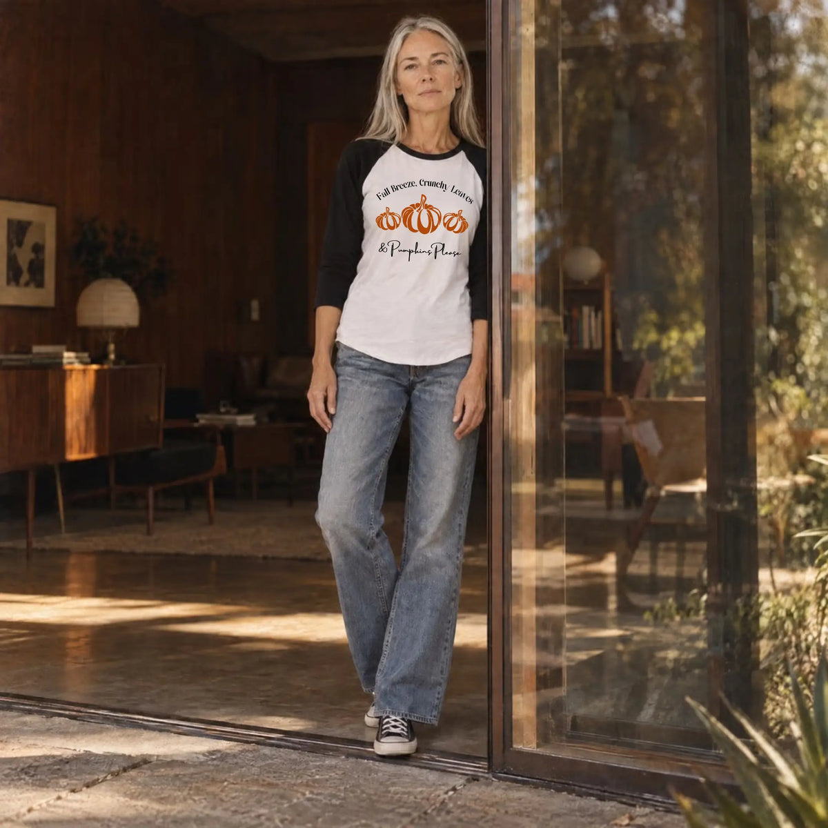 Woman in a white and black "Fall Breeze, Crunchy Leaves &amp; Pumpkins Please" raglan tee in an open glass doorway