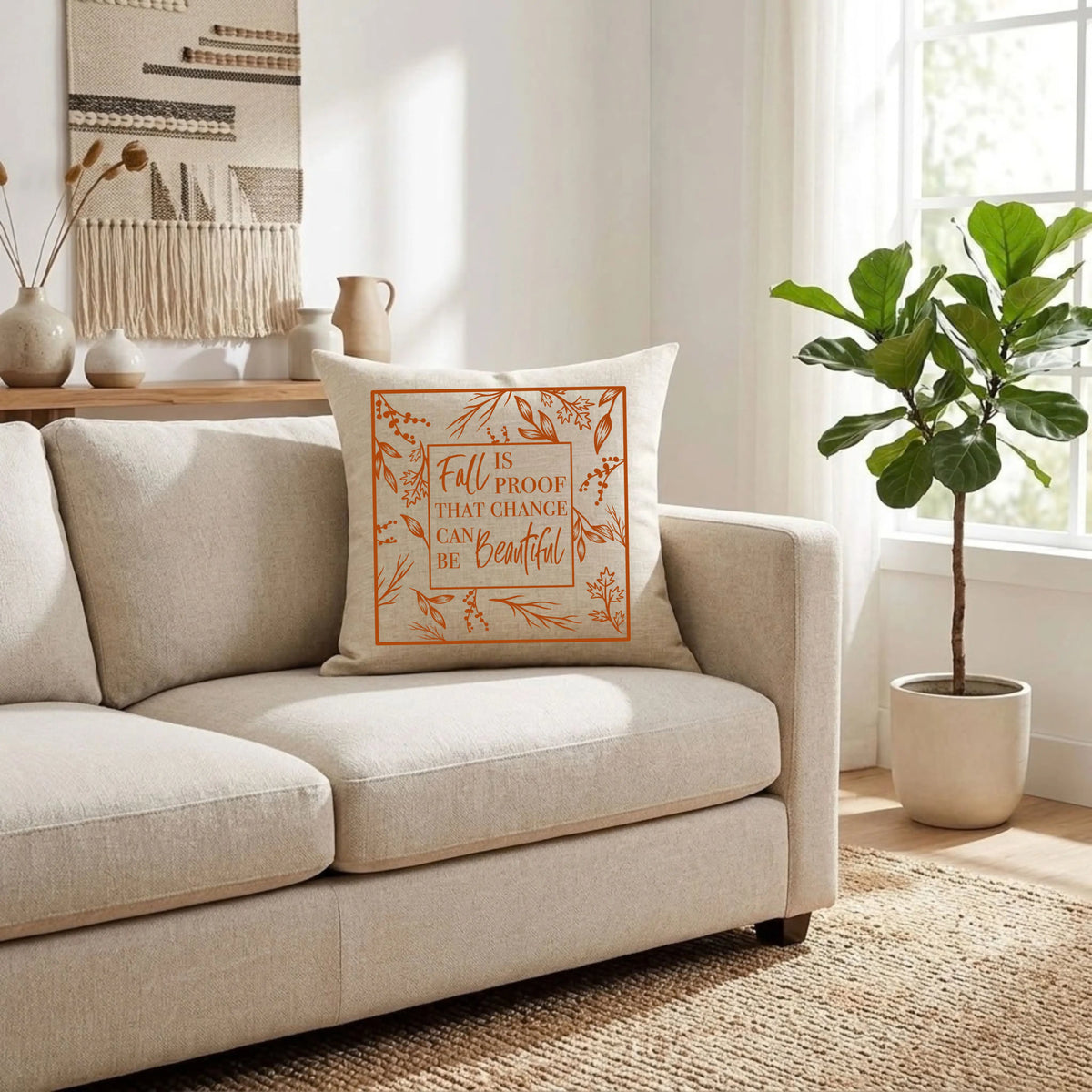 Natural linen throw pillow with a burnt orange "Fall Is Proof That Change Can Be Beautiful" quote on a cream sofa