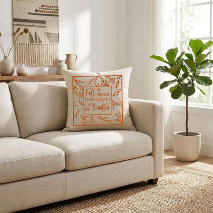 Natural linen throw pillow with a burnt orange "Fall Is Proof That Change Can Be Beautiful" quote on a cream sofa