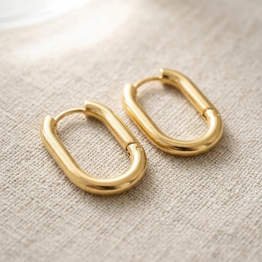 18K gold oval huggie earrings by Winks Design Studio, LLC, featuring sleek, polished hoop-style earrings with a secure clasp.