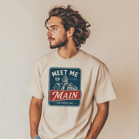 Man wearing a t-shirt with 'Meet Me on Main' design against a plain background