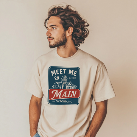 Man wearing a t-shirt with 'Meet Me on Main' design against a plain background
