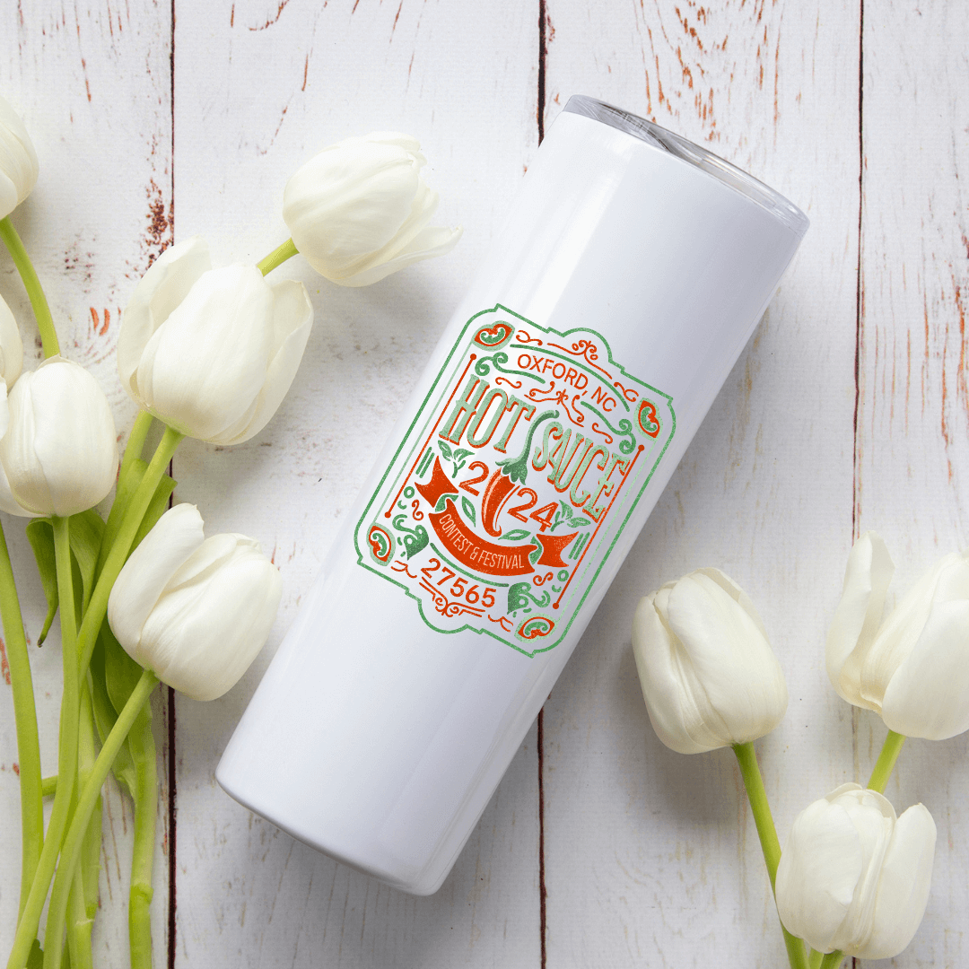 NC Hot Sauce 2024 Tumbler with Vintage Label Design among white tulips on wooden background