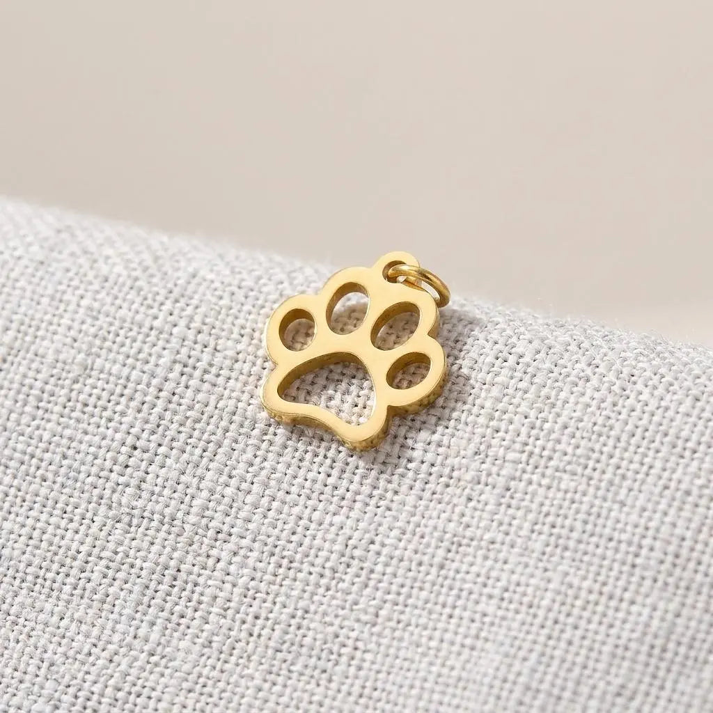 18K gold paw print charm by Winks Design Studio, LLC, featuring a detailed paw print design for jewelry or accessories.