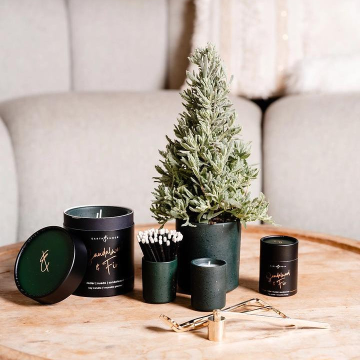 Decorative items including candles and a small tree on a wooden table with a neutral background.