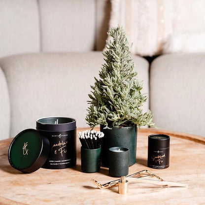 Decorative items including candles and a small tree on a wooden table with a neutral background.