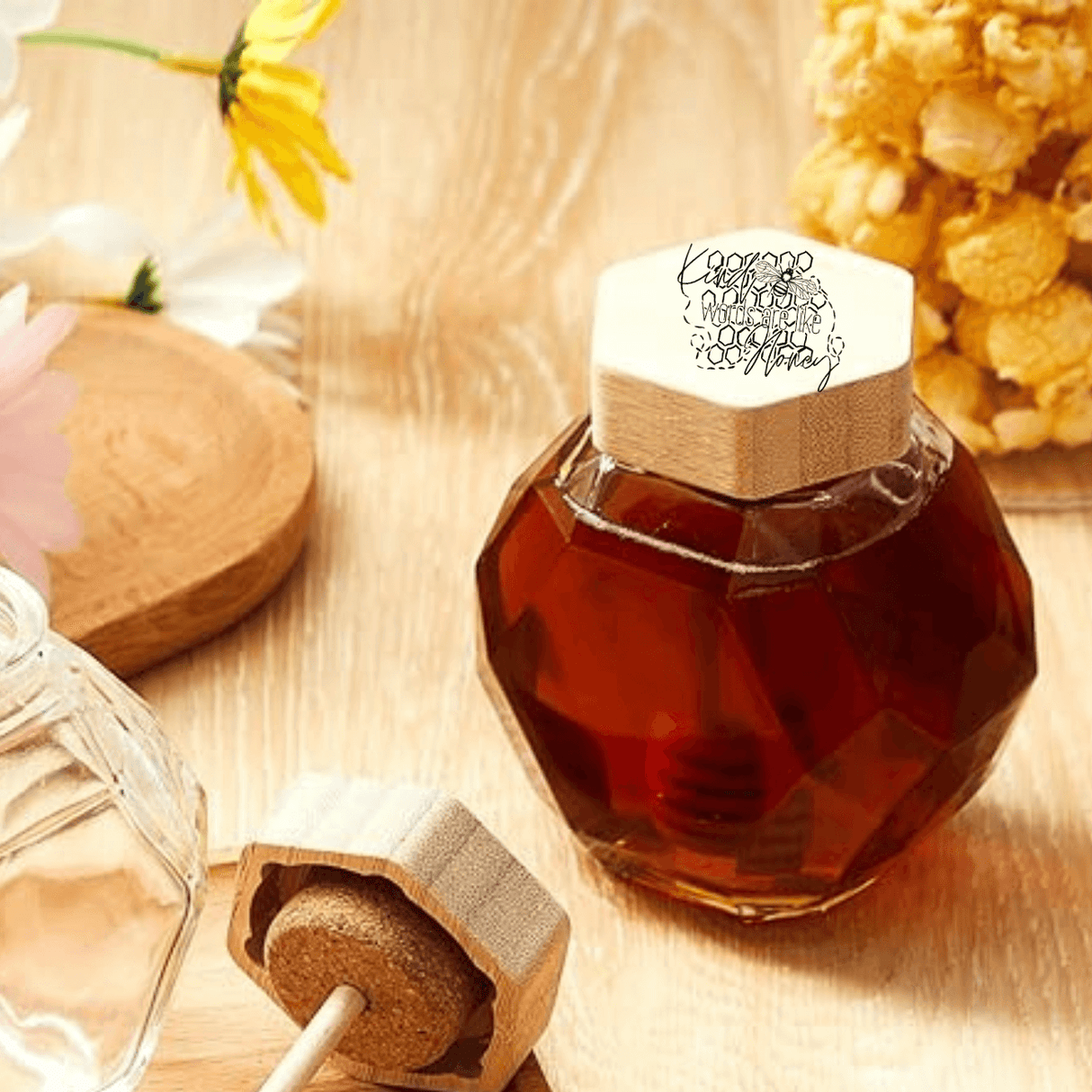 Elegant engraved hexagon glass honey dispenser with dipper and wooden lid, showcasing the "Kind Words Are Like Honey" design.