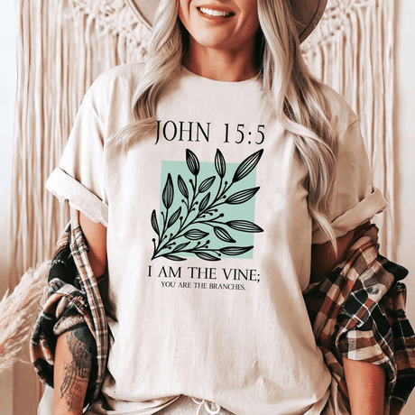 A woman wearing a tan shirt that says John 15:5 I am the vine